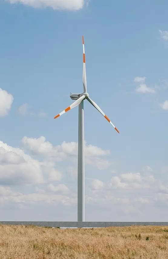 Una turbina eólica solitaria en un campo abierto bajo un cielo parcialmente nublado